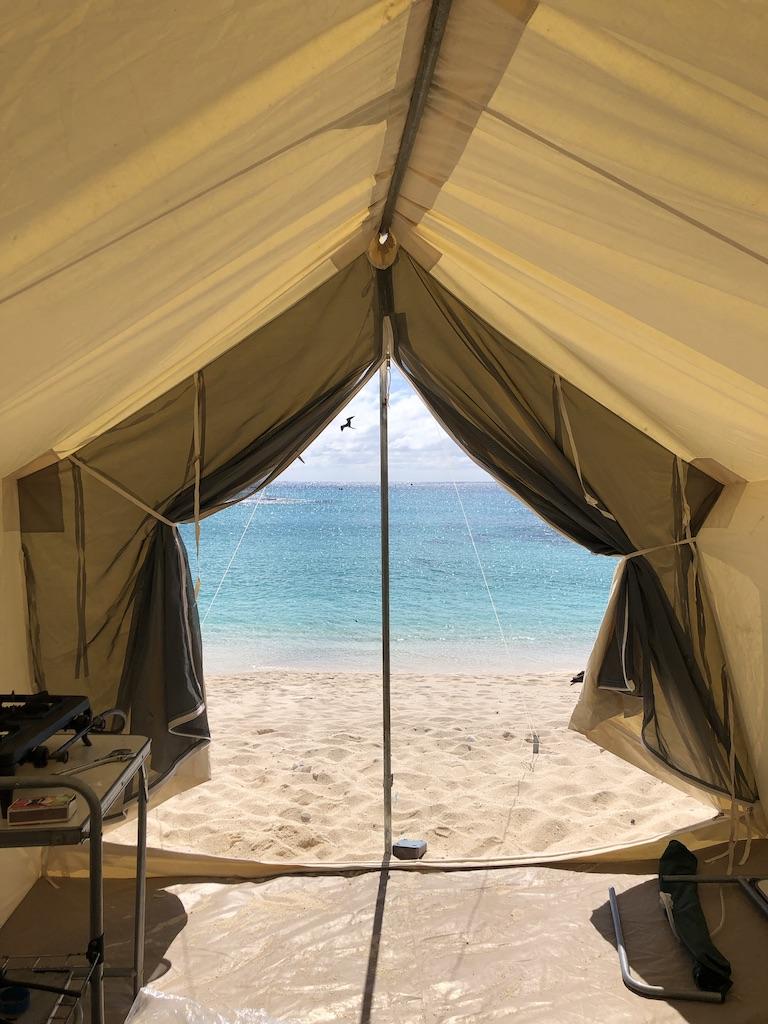 The inside of a camper's white tent, looking out at the ocean