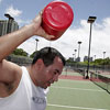 Photo of man pouring water on his head.