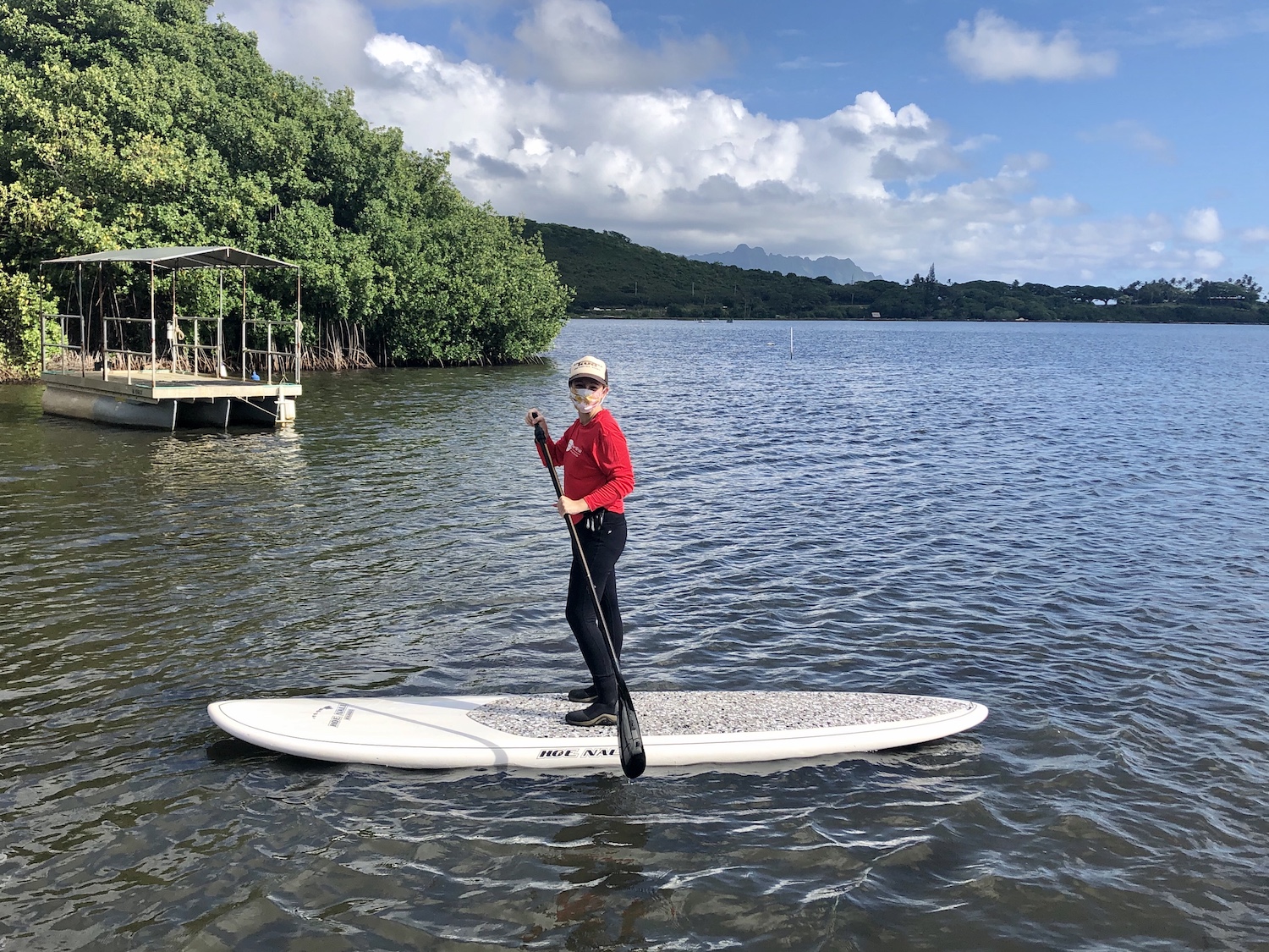 UH Mānoa graduate student Becca Lensing with the Alegado Lab sampling at Heʻeia Fishpond on a paddleboard with cloth mask on.