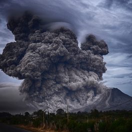 Mount Sinabung (volcano) in Indonesia erupts with a huge smoke and debris cloud. Cloudy skies are behind the volcano.