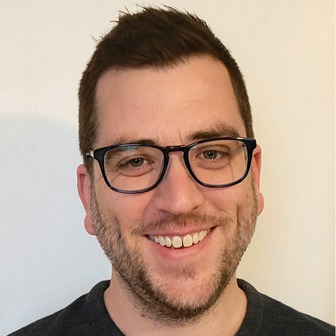 Headshot of Patrick Drupp, smiling with black rim glasses