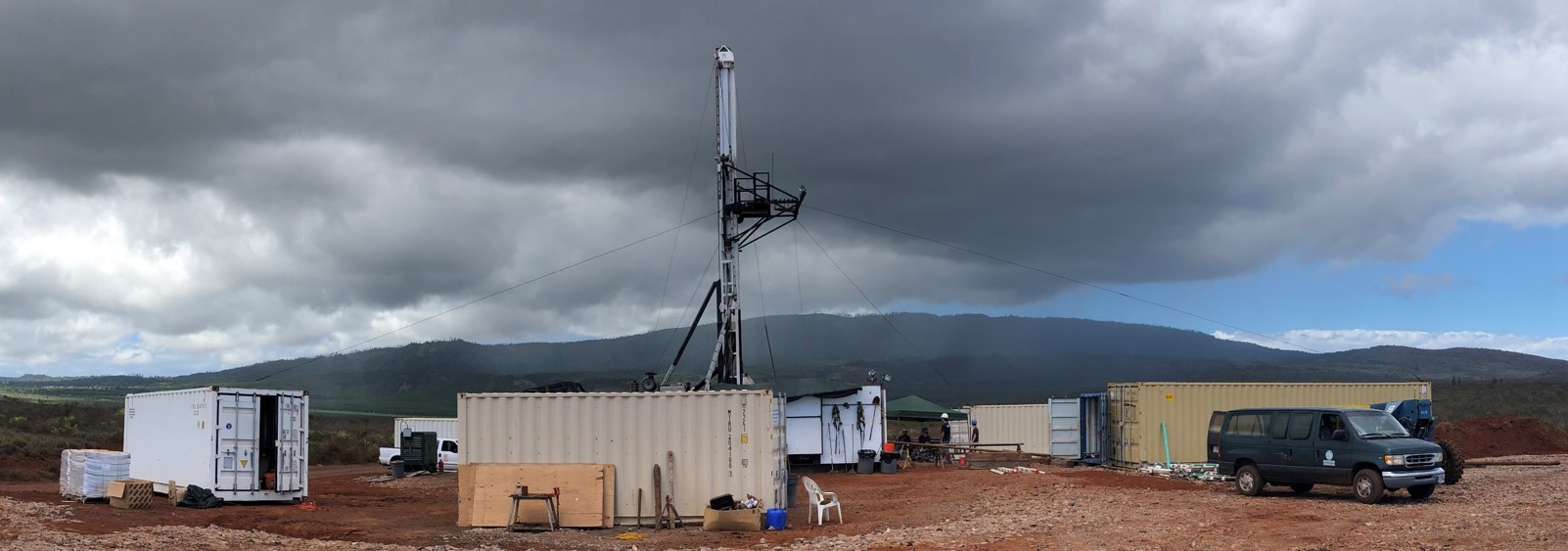 Drilling site at a water well in Palawai Basin, Lanai with shipping containers in the foreground, a pop-up tent in the background.