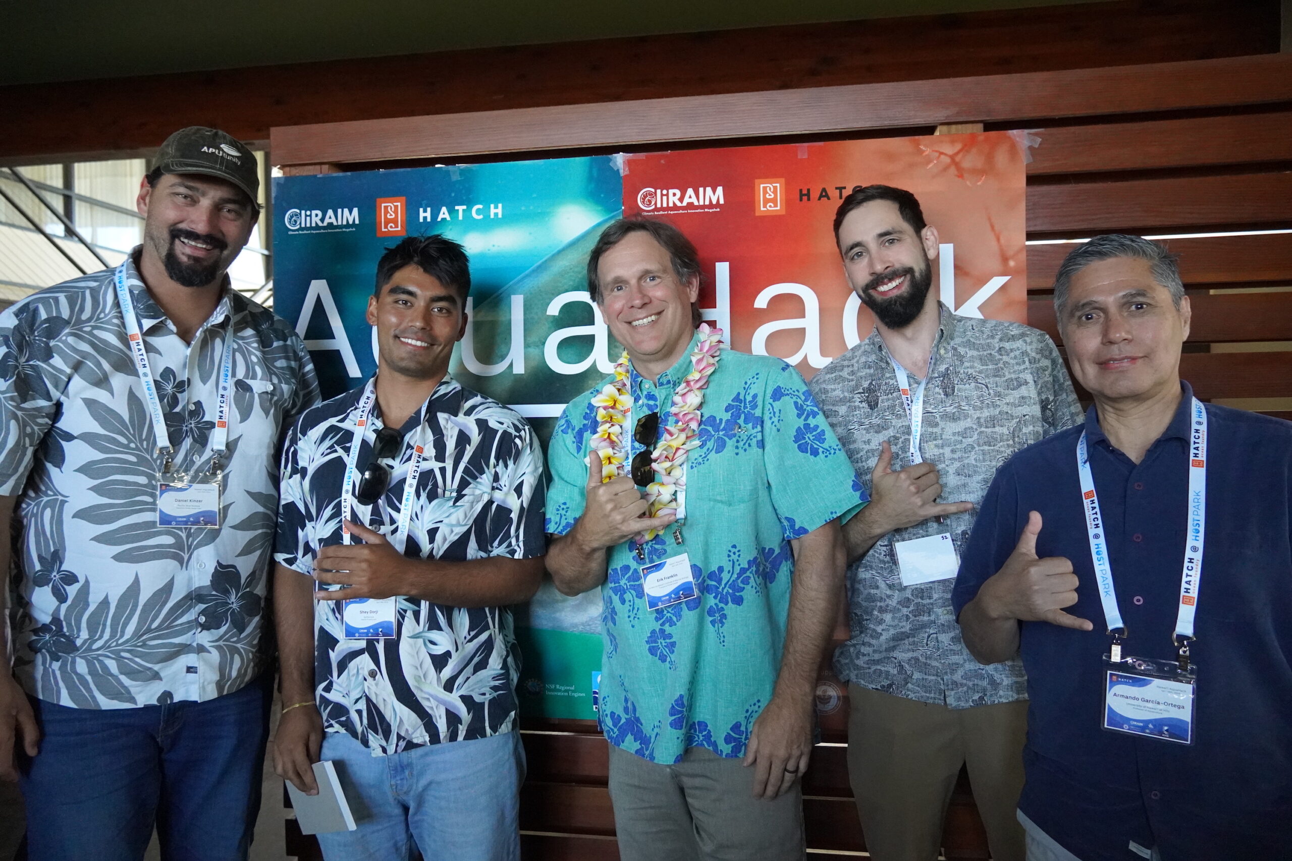 Five people in front of the AquaHack event sign