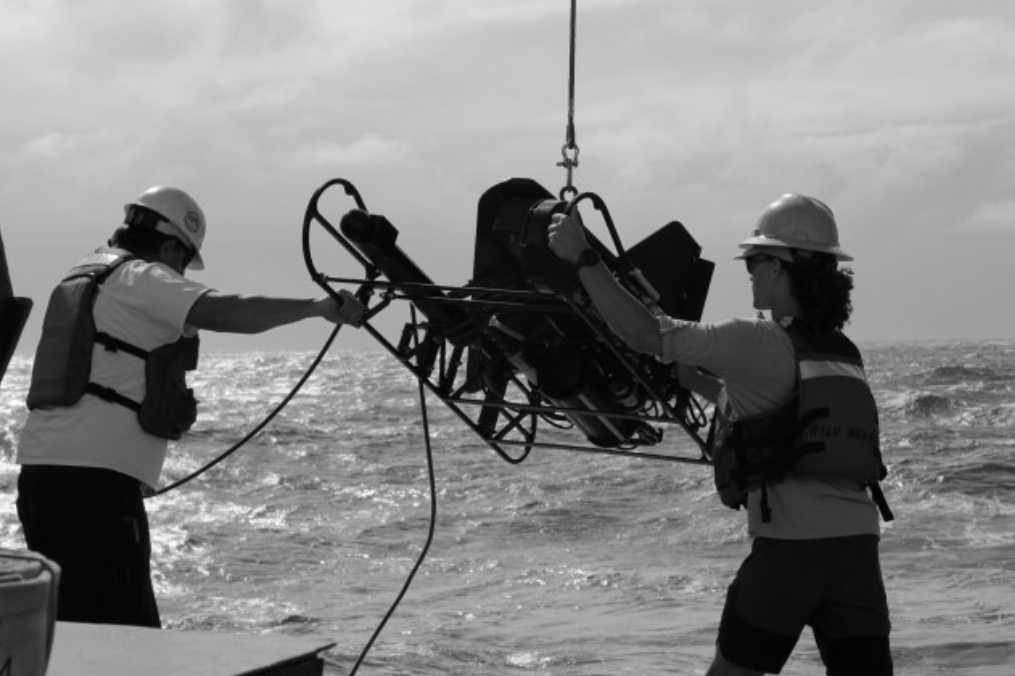 Two researchers steady a video plankton recorder on the back deck of the ship as they ready it for deployment.
