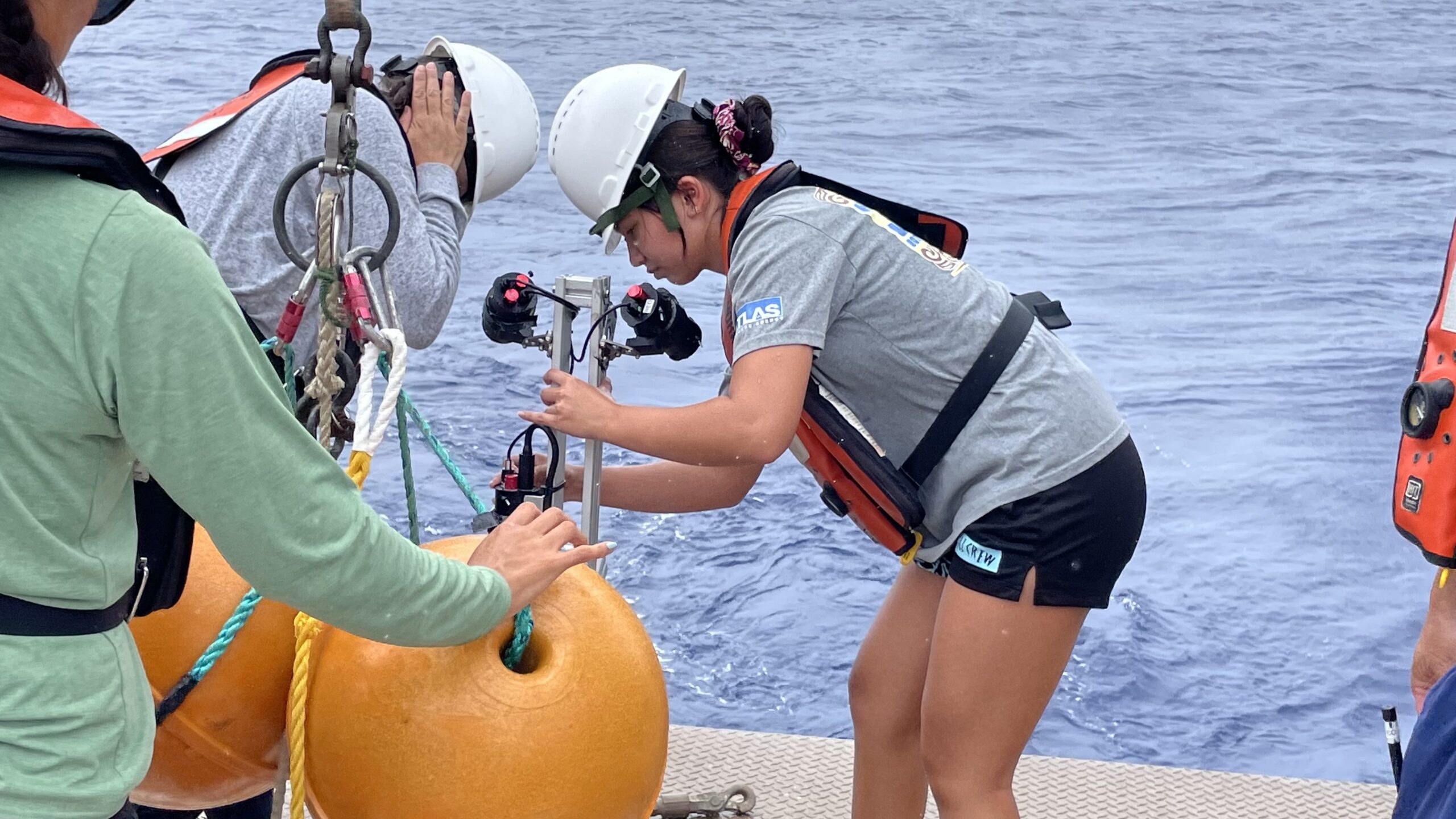 On the back deck of a research vessel, Malia Martin prepares to deploy an artificial light prototype that aids deep sea underwater camera surveys.