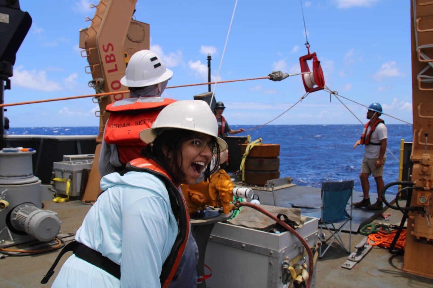 Prajna Jandial smiling on the back deck of the research vessel Oscar Sette.