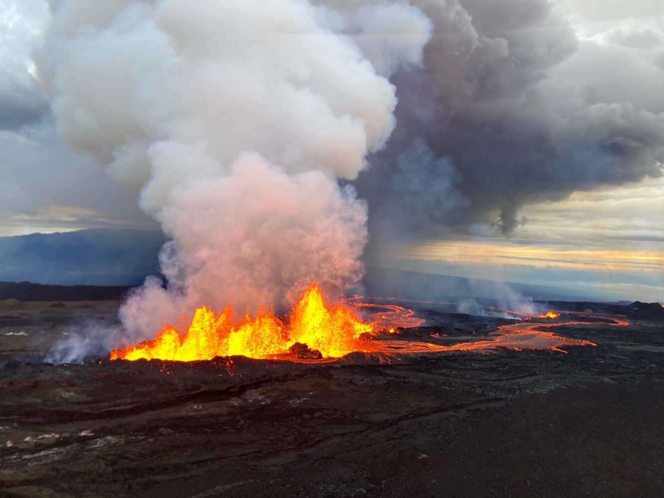 Maunaloa erupting in 2022 with a curtain of lava, a river of lava flowing, and smoke billowing from a fissure.