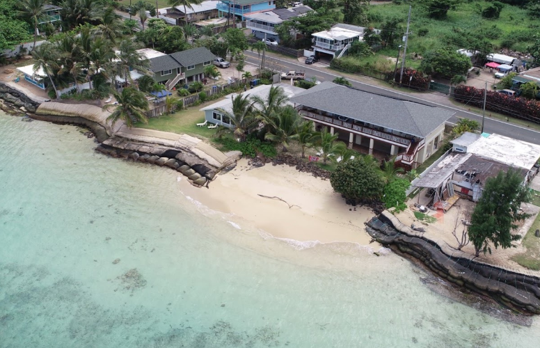 A residence with a small sandy beach flanked with temporary hardening structures, in Punalu‘u, O'ahu.