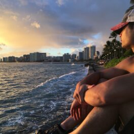 Ian Chung looks out over the ocean from shore at sunset in Waikiki, O'ahu